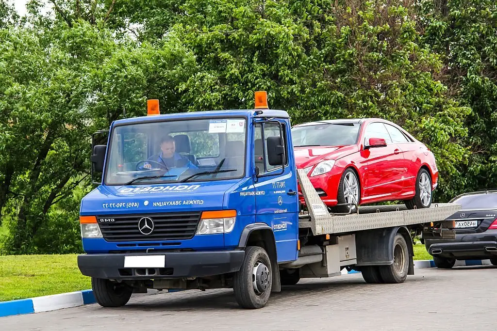 blue car is towing new red car